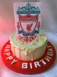 Night Owl Cakery Liverpool Football Club themed cake, covered with vanilla buttercream and a white chocolate drip coat. Decorated with a Liverpool emblem topper, sugar pearls and edible red glitter.