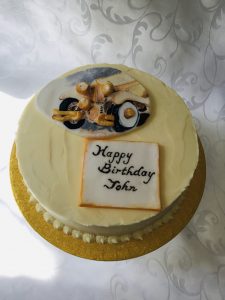 A lemon cake covered with lemon flavoured buttercream and decorated with our hand-sculpted and hand-painted sugar plaques
