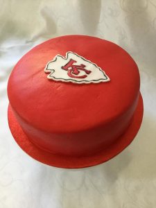 Acherry red iced cake with the logo an NFL team on top.